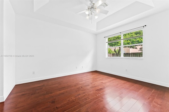 unfurnished room with ceiling fan, hardwood / wood-style floors, and a tray ceiling