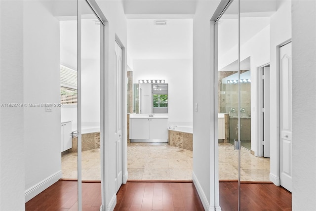 interior space with vanity, a wealth of natural light, hardwood / wood-style floors, and shower with separate bathtub