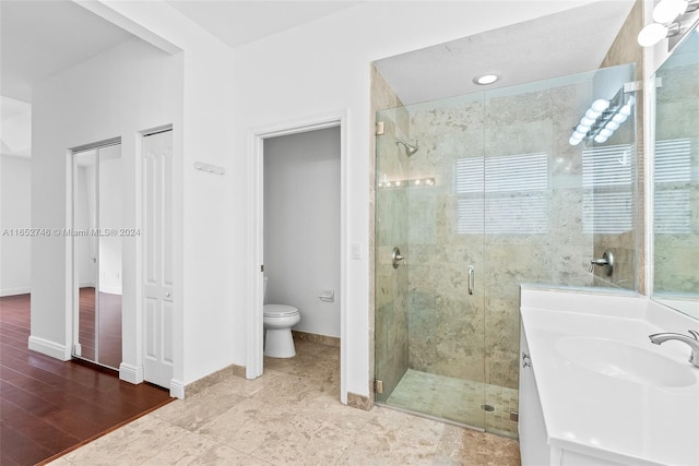 bathroom featuring vanity, toilet, hardwood / wood-style flooring, and an enclosed shower