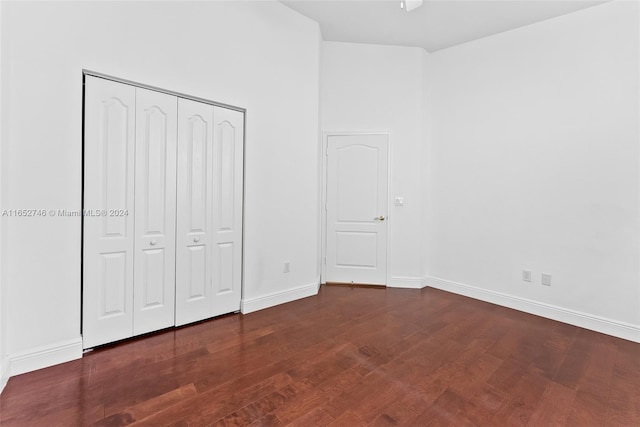 unfurnished bedroom with dark wood-type flooring and a closet