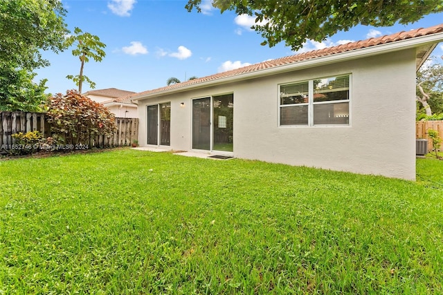 rear view of house with a yard and central AC