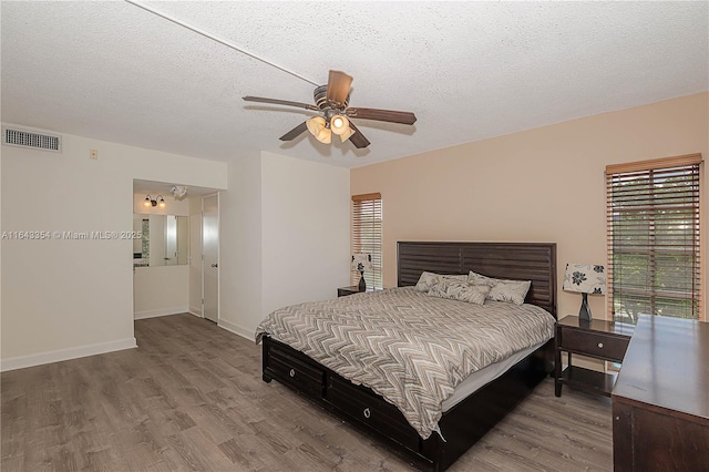 bedroom with baseboards, visible vents, a ceiling fan, wood finished floors, and a textured ceiling