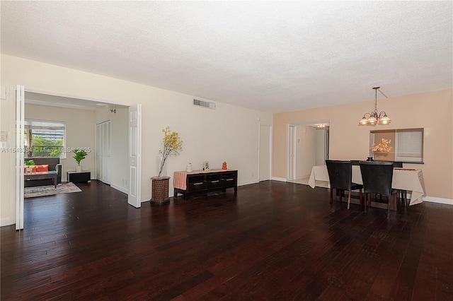 dining area featuring a textured ceiling, wood-type flooring, visible vents, and an inviting chandelier