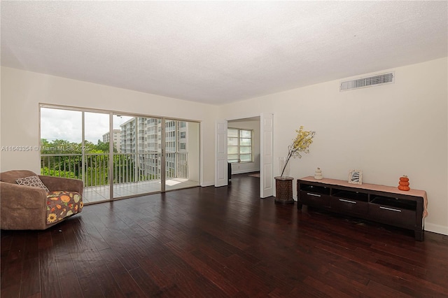 living area featuring hardwood / wood-style flooring, baseboards, visible vents, and a textured ceiling