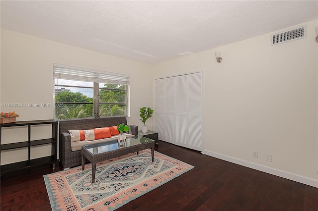 interior space featuring baseboards, visible vents, a textured ceiling, and hardwood / wood-style floors