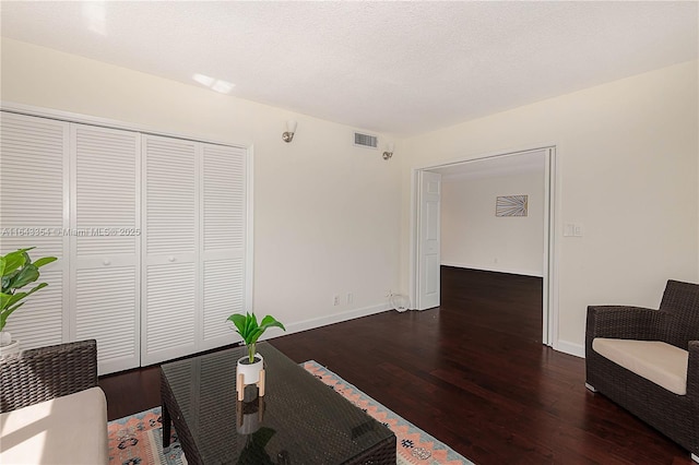 sitting room featuring a textured ceiling, wood finished floors, visible vents, and baseboards