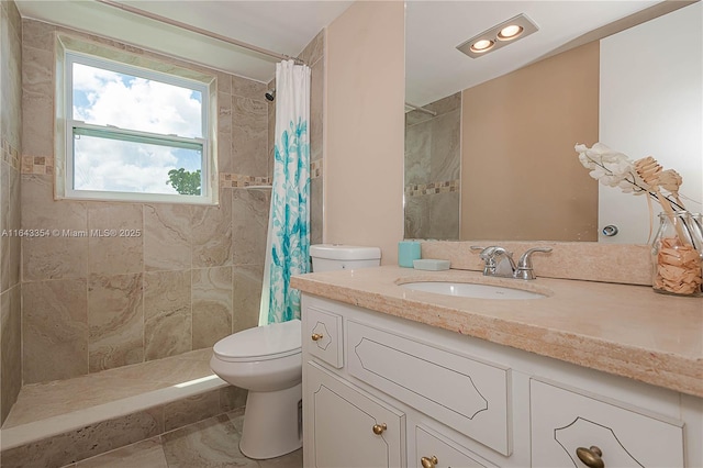 bathroom featuring a tile shower, vanity, and toilet