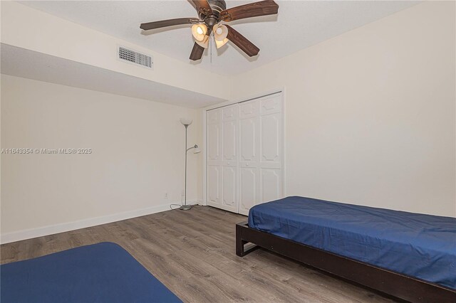 bedroom with wood-type flooring, a closet, and ceiling fan