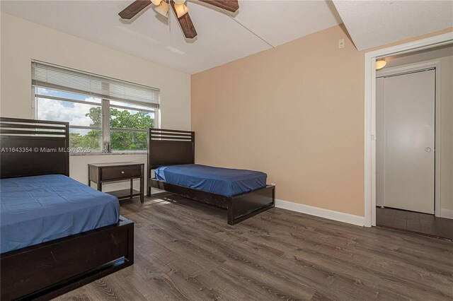 bedroom featuring dark hardwood / wood-style floors, ceiling fan, and a textured ceiling