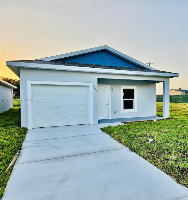 view of front of house with a garage, a lawn, concrete driveway, and stucco siding