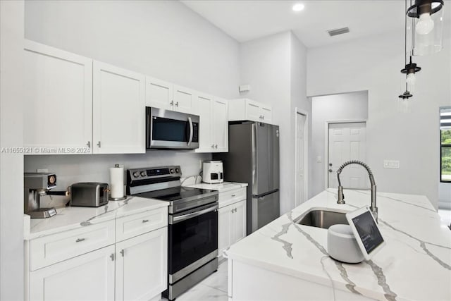 kitchen featuring appliances with stainless steel finishes, hanging light fixtures, light stone countertops, and sink