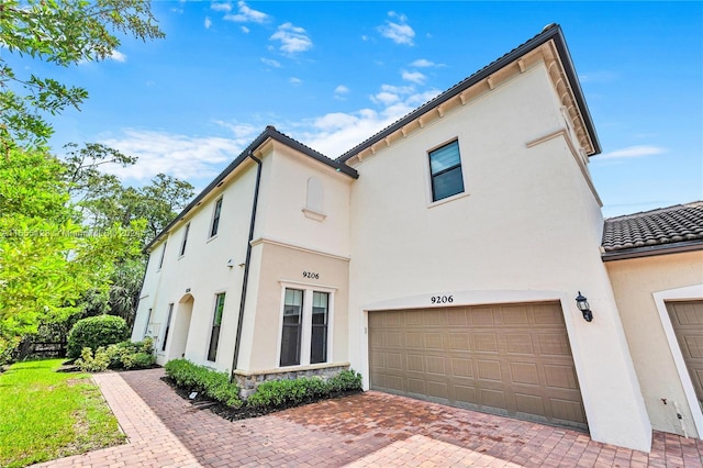 9206 Passiflora Way Unit 101, Boca Raton, FL 33428 - view of front of property featuring stucco siding, an attached garage, decorative driveway, a tile roof, and stone siding