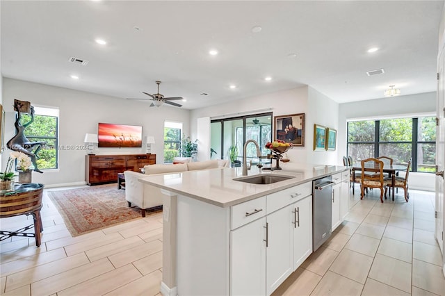 kitchen with ceiling fan, white cabinets, sink, a kitchen island with sink, and dishwasher