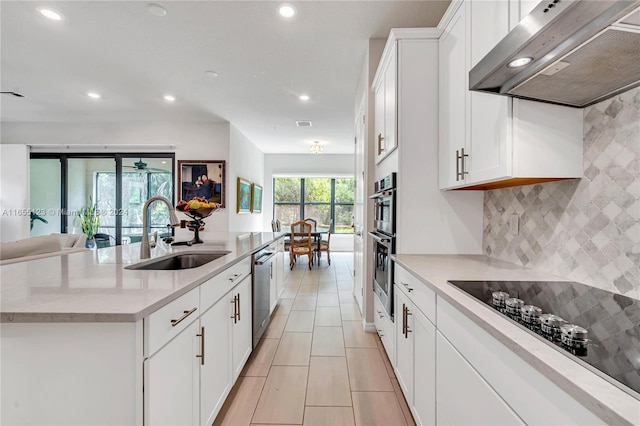 kitchen featuring an island with sink, sink, extractor fan, white cabinetry, and stainless steel appliances