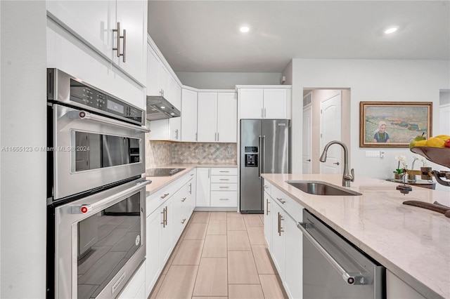 kitchen featuring ventilation hood, stainless steel appliances, sink, and white cabinetry