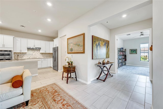 interior space featuring appliances with stainless steel finishes, white cabinetry, a breakfast bar, tasteful backsplash, and ceiling fan