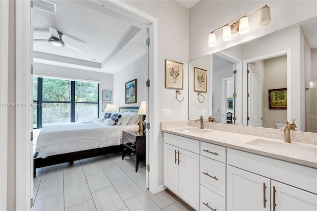 bathroom with a raised ceiling, tile patterned floors, ceiling fan, vanity, and toilet