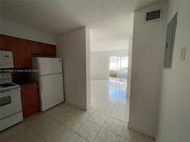 kitchen featuring a textured ceiling, white appliances, electric panel, and light tile patterned flooring