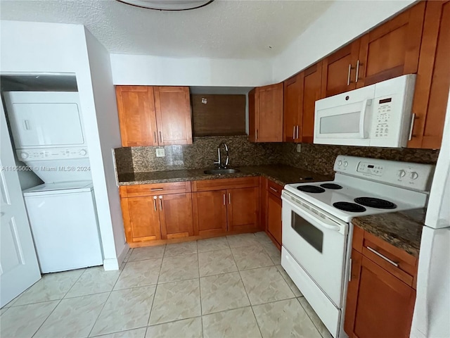 kitchen with sink, backsplash, stacked washer and dryer, a textured ceiling, and white appliances