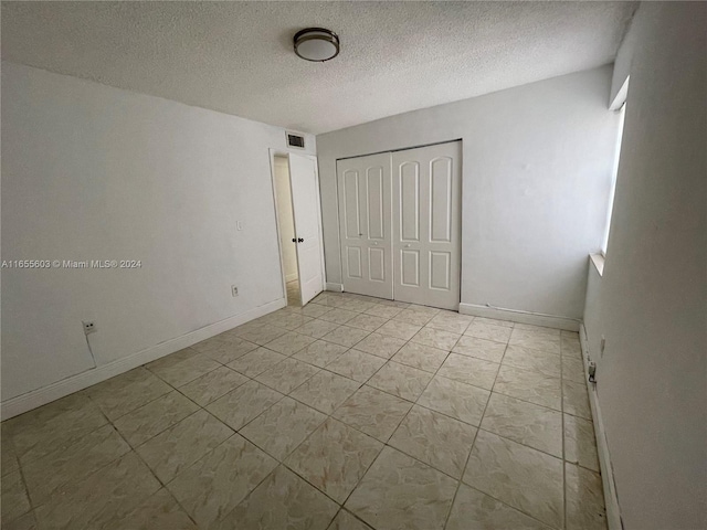 unfurnished bedroom with a closet, light tile patterned floors, and a textured ceiling