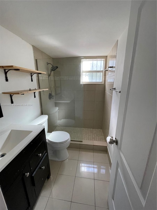 bathroom with tile patterned floors, vanity, toilet, and a tile shower