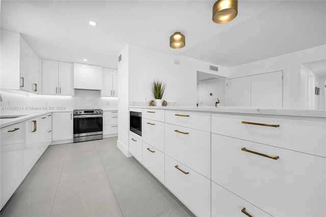 kitchen with white cabinetry, sink, built in microwave, electric stove, and light tile patterned floors