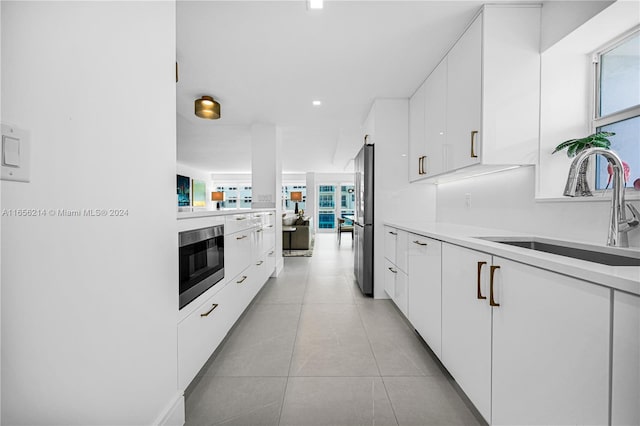 kitchen with appliances with stainless steel finishes, white cabinetry, a wealth of natural light, and sink