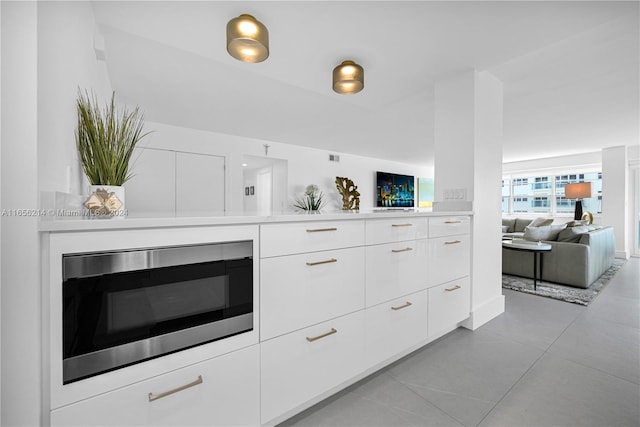 kitchen featuring white cabinets, light tile patterned floors, and stainless steel microwave