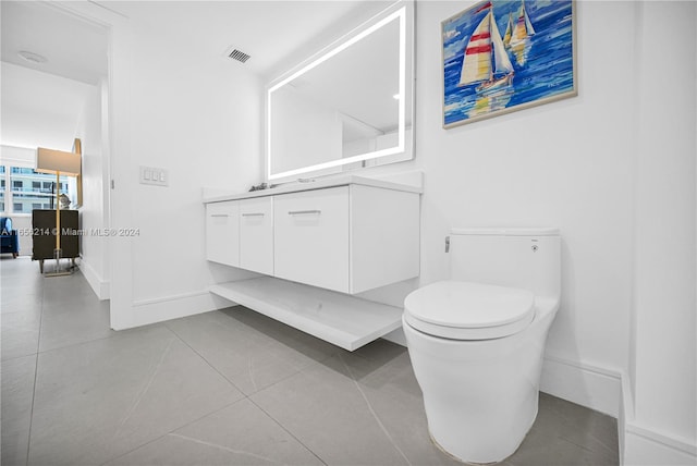 bathroom with toilet, vanity, and tile patterned floors