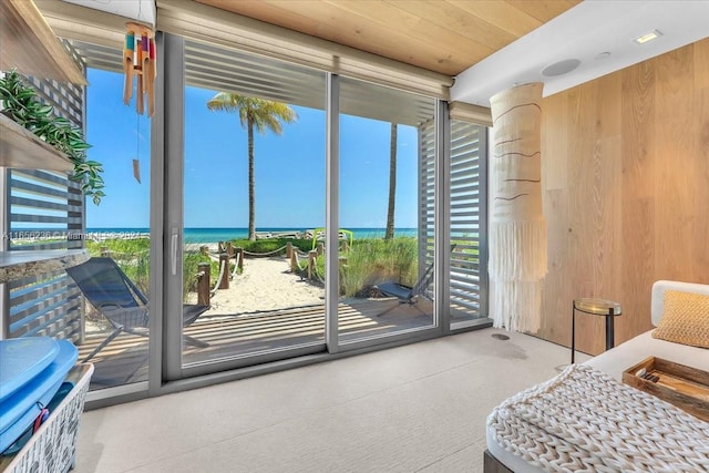 carpeted bedroom featuring a water view, wooden walls, and access to outside