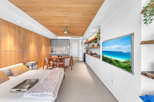 living room with wood walls, recessed lighting, wooden ceiling, a raised ceiling, and a ceiling fan