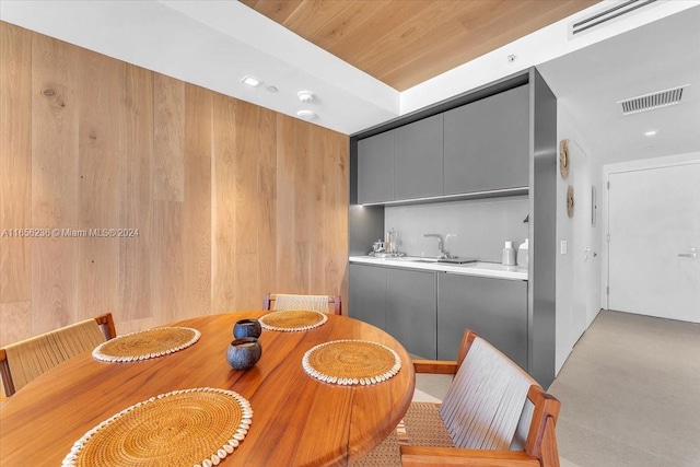 dining room featuring wood ceiling, sink, and wooden walls