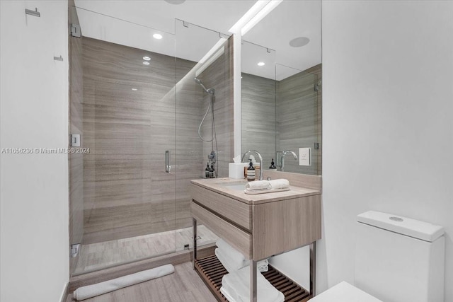 bathroom with vanity, toilet, wood-type flooring, and a shower with door