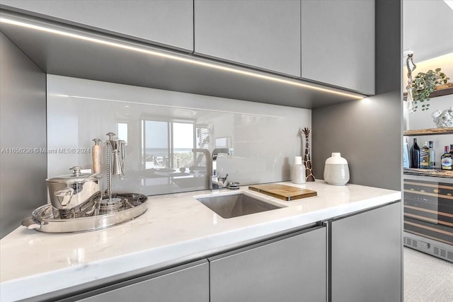 kitchen featuring modern cabinets, gray cabinets, a sink, wine cooler, and light countertops