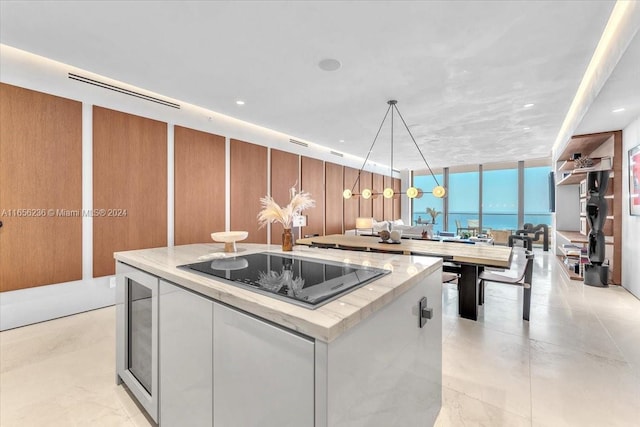 kitchen featuring hanging light fixtures, white cabinetry, black electric cooktop, wine cooler, and a kitchen island