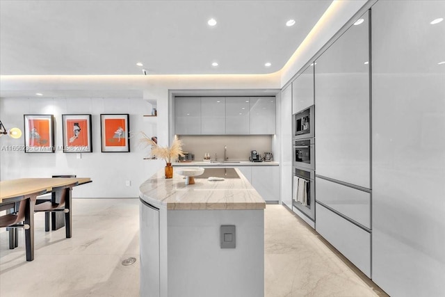 kitchen with gray cabinetry, stainless steel appliances, a center island, and sink