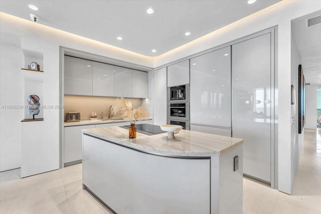 kitchen featuring modern cabinets, a sink, a center island, light tile patterned floors, and black electric stovetop