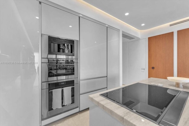 kitchen featuring stainless steel double oven, black electric cooktop, and light tile patterned floors