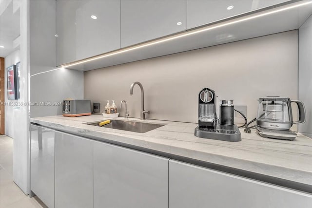 kitchen with white cabinets, light stone countertops, modern cabinets, and a sink