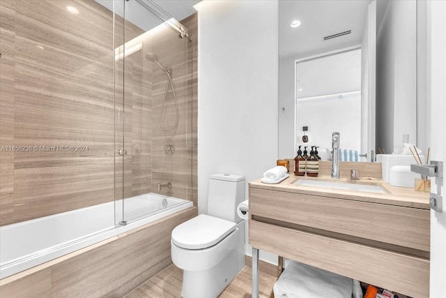 full bathroom featuring hardwood / wood-style floors, toilet, bath / shower combo with glass door, and vanity