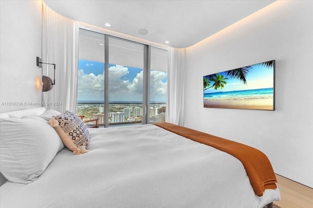 bedroom featuring a wall of windows, wood finished floors, and access to outside