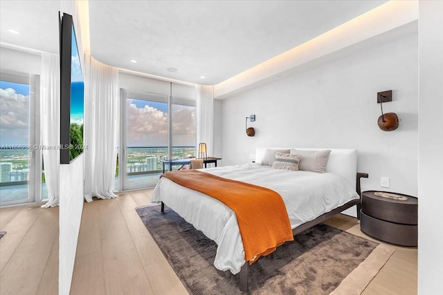 bedroom with light wood-type flooring, expansive windows, and access to outside