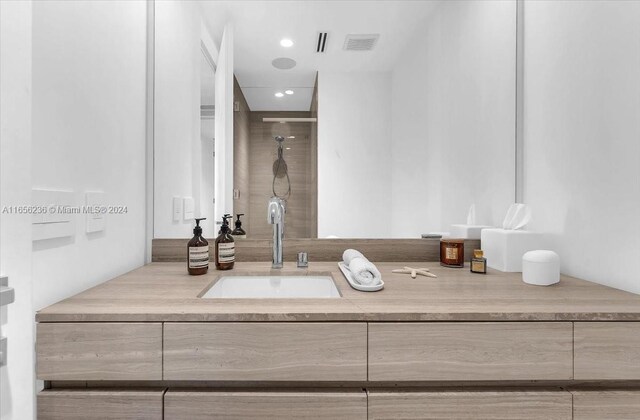 bathroom with tiled shower and vanity