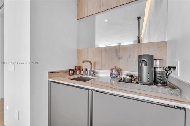 kitchen featuring a sink, light stone counters, modern cabinets, and light brown cabinets