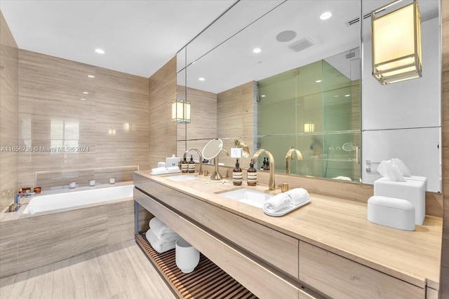 bathroom featuring visible vents, a garden tub, a sink, tile walls, and double vanity