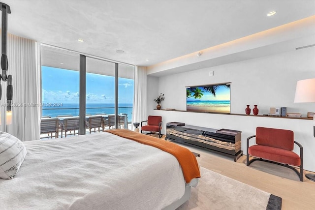 bedroom with a water view, a wall of windows, access to outside, and light hardwood / wood-style flooring