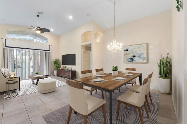 dining space with vaulted ceiling, light tile patterned flooring, ceiling fan with notable chandelier, and a healthy amount of sunlight