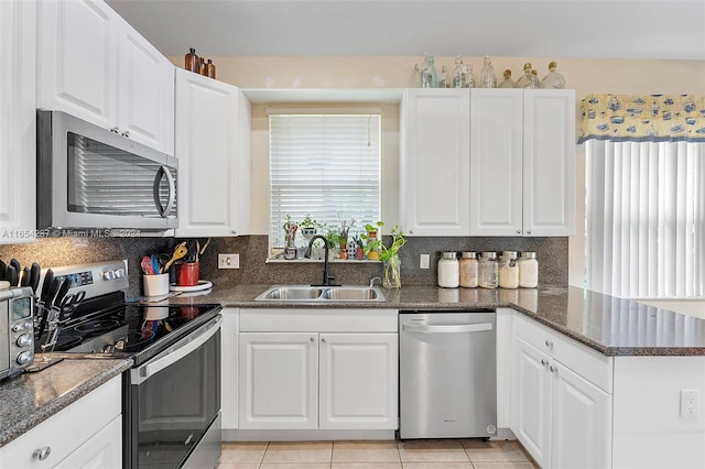 kitchen with sink, white cabinets, stainless steel appliances, and dark stone counters