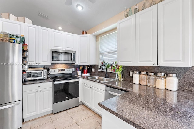 kitchen featuring sink, stainless steel appliances, lofted ceiling, white cabinets, and light tile patterned floors