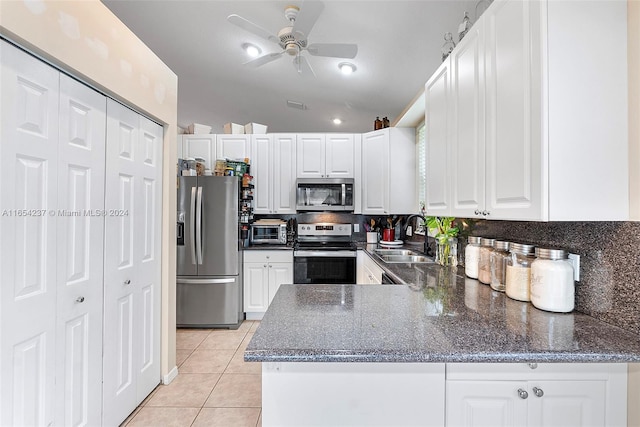 kitchen with kitchen peninsula, white cabinets, appliances with stainless steel finishes, vaulted ceiling, and sink